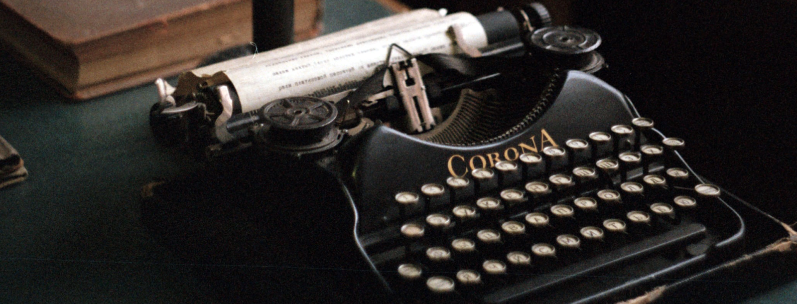 An old typewriter on a desk with books