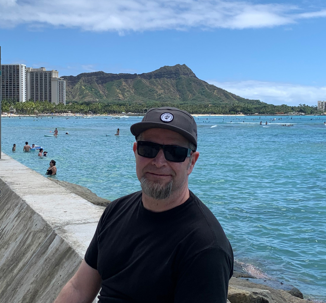 A picture of me on a pier at Waikiki Beach, with inviting blue water and Diamond Head in the background.