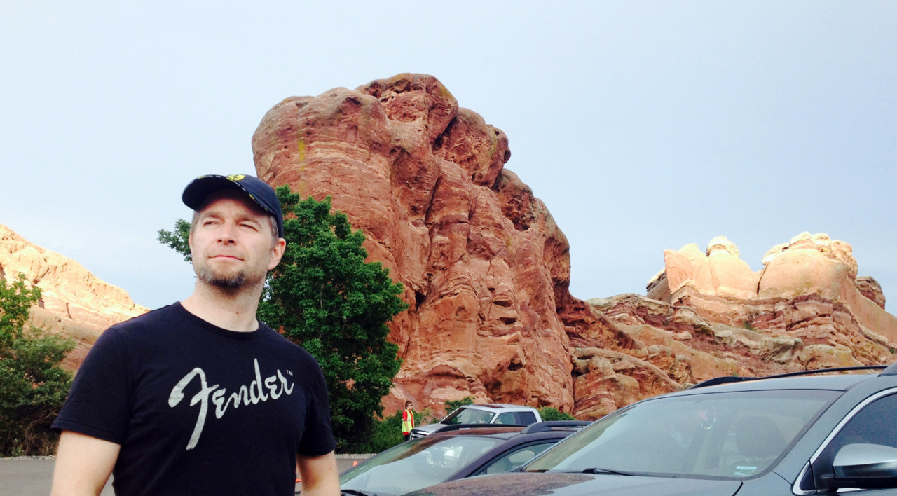 Me at Red Rocks Amphitheater in Denver, contemplative look on my face, with interesting rock formations in the background.